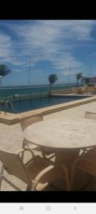 a table and chairs with the ocean in the background at Apart-Hotel na Praia do Farol da Barra in Salvador