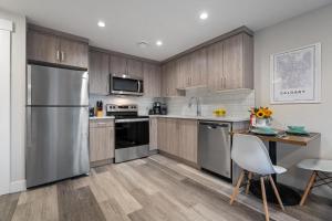 a kitchen with wooden cabinets and a stainless steel refrigerator at Contemporary 1br Home Full Kitchen Smarttv in Calgary