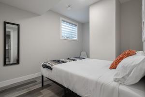 a white bedroom with a bed and a window at Contemporary 1br Home Full Kitchen Smarttv in Calgary