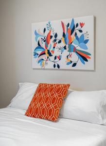 uma cama com uma almofada laranja e um quadro na parede em Contemporary 1br Home Full Kitchen Smarttv em Calgary