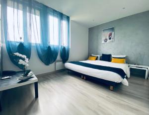 a bedroom with a large bed with blue curtains at Hotel Air-lane in Saint-Léger-sous-Brienne