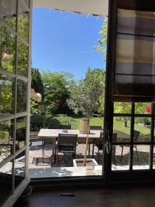 Blick auf einen Tisch und Stühle durch ein Fenster in der Unterkunft La Collinière in Sainte-Gemme-Moronval