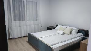 Vila Maksim Sokobanja في سوكو بانيا: سرير بشرشف ووسائد بيضاء في الغرفة