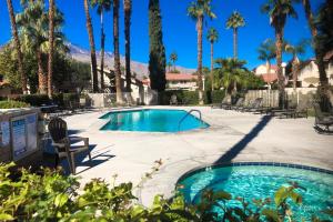 a pool with a chair and palm trees at Mountain Shadows Condo in Palm Springs