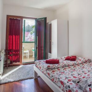 sypialnia z łóżkiem z czerwonymi poduszkami w obiekcie GLORIA Apartman w mieście Žabljak