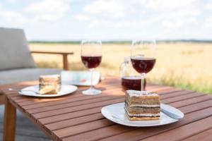 un tavolo con due fette di torta e due bicchieri di vino di Hiša iz volne a Moravske Toplice