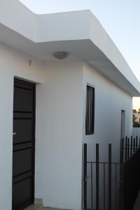 a white house with a black door and a fence at Hotel Bugambilias in Ciudad Obregón