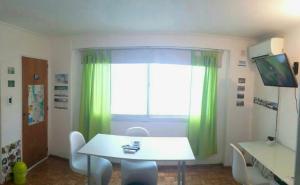 Habitación con mesa y ventana con cortinas verdes. en Isla Verde en Rosario