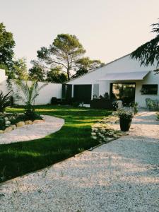 a home with a gravel driveway and a white building at Gîte les 2 cèdres in Cardet
