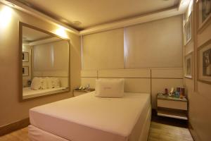 a small bedroom with a bed and a mirror at LESSENCE MOTEL in São Paulo +14 photos