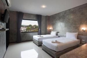 a bedroom with two beds and a large window at Ritsurin Boutique Hotel - โรงแรมริทสุริน บูติค in Phuket Town