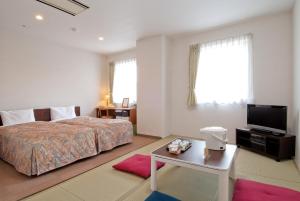 a bedroom with a bed and a tv and a table at Hotel New Ohte in Hakodate