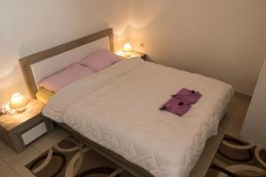 ein Schlafzimmer mit einem weißen Bett mit violetter Bettwäsche und zwei Lampen in der Unterkunft Apartment in Mundanije with terrace, air conditioning, WiFi (4912-2) in Mundanije