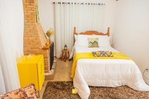 um quarto com uma cama com um cobertor amarelo e branco em Chalés Recanto da cachoeira em Monte Verde