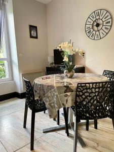 mesa de comedor con sillas y reloj en la pared en Residence Soleil des Thermes 2, en Le Mont-Dore