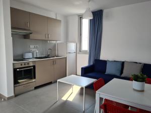 een keuken en een woonkamer met een blauwe bank en een tafel bij Tefkrou Anthia 9 apts in Ayia Napa