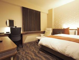 a hotel room with a bed and a desk and chair at Hotel Fukuoka Garden Palace in Fukuoka