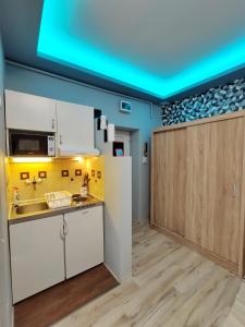 uma cozinha com armários brancos e um tecto azul em Belvarosi Exkluzív Minigarzon em Debrecen