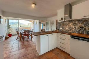 a kitchen with white cabinets and a dining room with a table at Attique à Banyuls - vue mer et montagne in Banyuls-sur-Mer