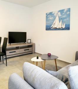 a living room with a tv and a sail boat on the wall at Sea Star Apartments in Pješčana Uvala