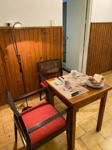 a wooden table with a red chair and a table and chairsuggest at Lo de Lala B&B con Energía Solar in Acassuso