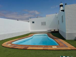 a swimming pool in the backyard of a white building at Apartamentos Anjomacar II in Teguise