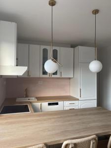 a kitchen with white cabinets and a table with two lights at Gala Posh in Soko Banja