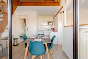 une salle à manger avec une table et des chaises bleues dans l'établissement Duplex by the sea in Normandy, à Villers-sur-Mer
