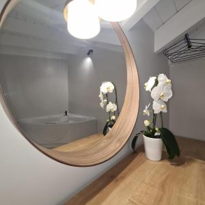 a round mirror on a wall in a room with flowers at ILIA'S Luxury Suites in Xylokastron