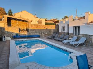 a swimming pool with chairs and a house at Casa Olivia villa in Arboleas