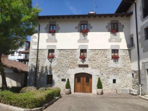 un gran edificio de piedra con flores en la puerta en Alojamiento Rural URGAIN I y II, en Lekunberri