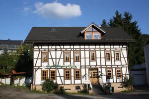 un grand bâtiment blanc avec un toit noir dans l'établissement Gasthof zur Post, à Siegen