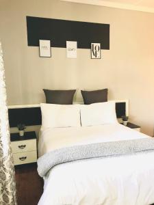 a bedroom with a white bed with a black headboard at VnA Guesthouse in Newcastle