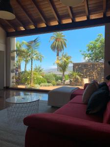 Una sala de estar con un sofá rojo y una gran ventana. en Casa La Masía, en La Orotava