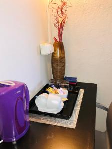 VnA Guesthouse في نيوكاسل: طاولة مع محمصة أرجوانية و مزهرية
