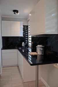 a kitchen with black counter tops and white cabinets at Osiedle Centrum Miasta in Suwałki