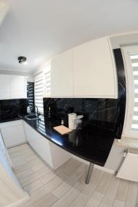 a kitchen with a black counter and white cabinets at Osiedle Centrum Miasta in Suwałki