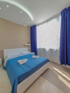 um quarto com uma cama com lençóis azuis e uma janela em Al Mare em Gallipoli