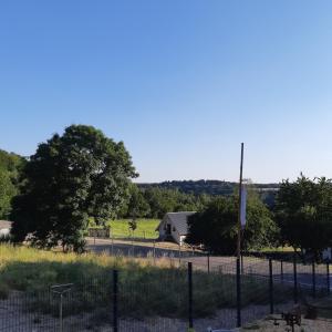 uma cerca em frente a um campo com uma casa em Am Hohestein em Briedeler Heck