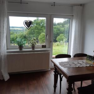 ein Wohnzimmer mit einem Tisch und einem Fenster mit einem Herz in der Unterkunft Am Hohestein in Briedeler Heck