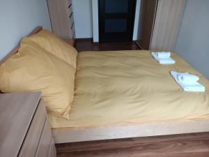 a bed with yellow sheets and two towels on it at Apartament Mimi in Gdynia