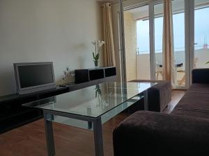 a living room with a glass table and a television at Apartament Mimi in Gdynia