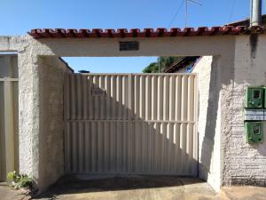 a gate to a house with a white fence at CASA TEMPORADA - PARA 05 PESSOAS in Trindade