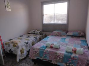 a bedroom with two beds and a window at CASA TEMPORADA - PARA 05 PESSOAS in Trindade