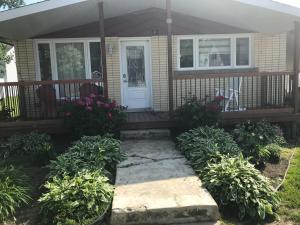 a front porch of a house with a white door at Le Gîte du Pêcheur in Metabetchouan
