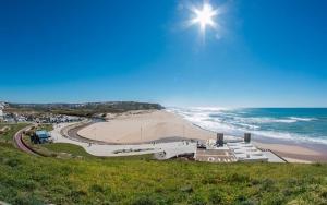 Blick auf einen Strand mit der Sonne darüber in der Unterkunft Apartment by the Beach Praia da Areia Branca in Lourinhã