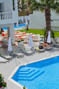 - un groupe de personnes assis sur des chaises à côté d'une piscine dans l'établissement Princessa Vera Hotel Apartments, à Paphos