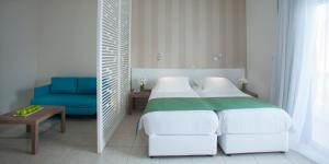 a bedroom with two beds and a blue chair at Princessa Vera Hotel Apartments in Paphos