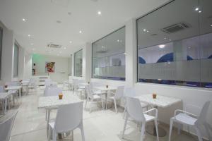 a restaurant with white tables and chairs and windows at Princessa Vera Hotel Apartments in Paphos