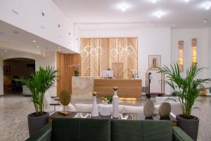 a lobby with a green couch and potted plants at My Way Hotel & Events in Patra